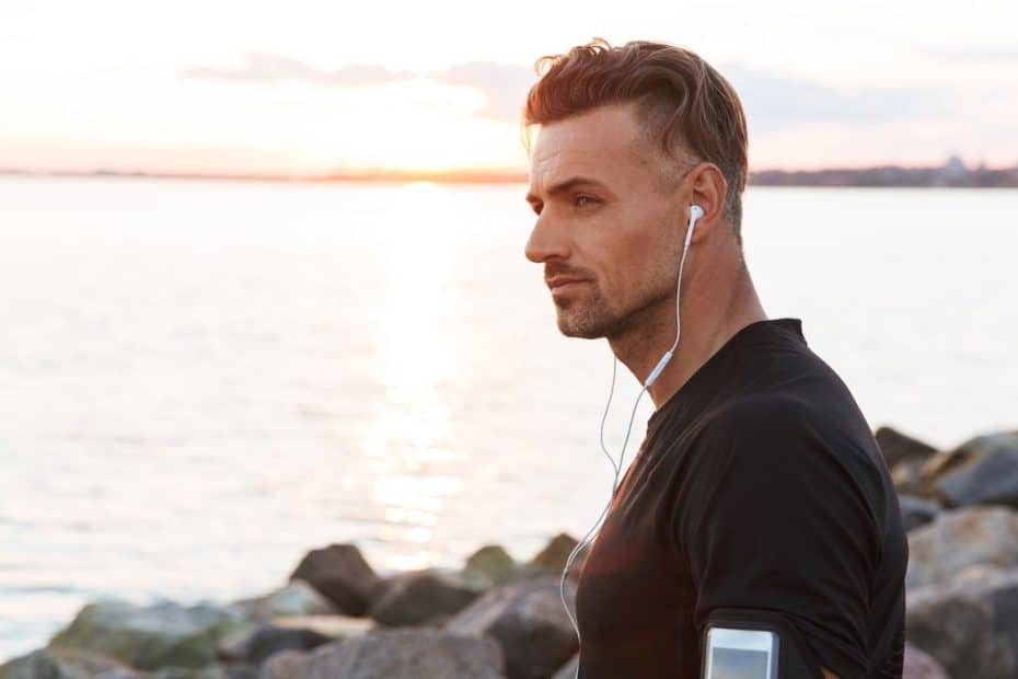 Man with earphones by the sea at sunrise