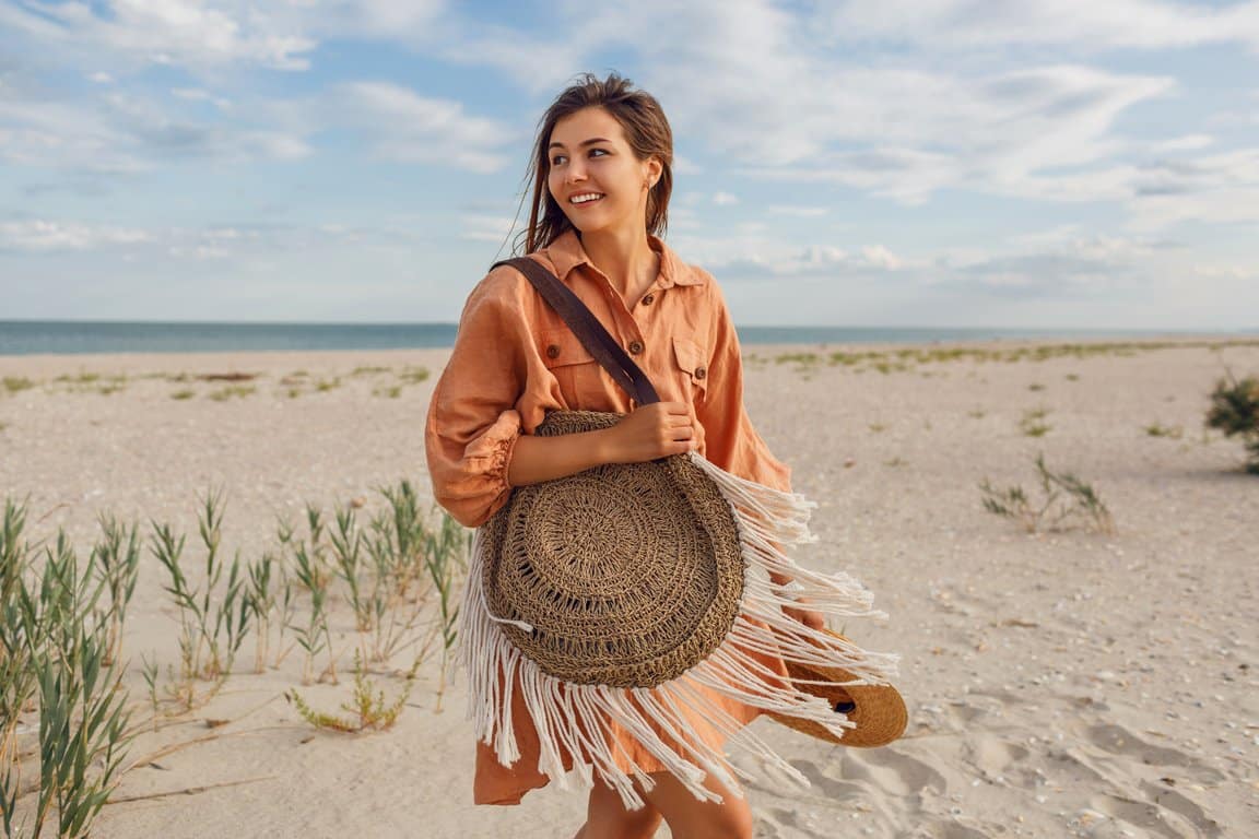 Woman with a woven bag walking on a beach