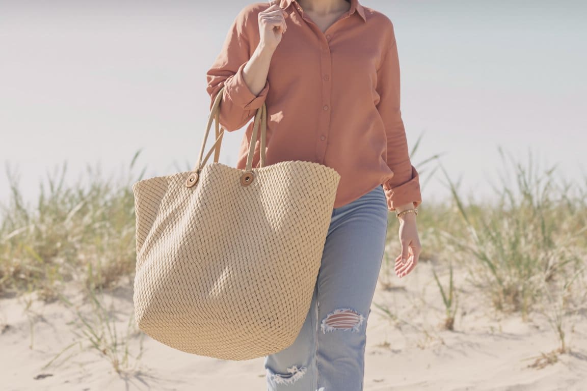 Woman carrying a woven beach bag in the dunes